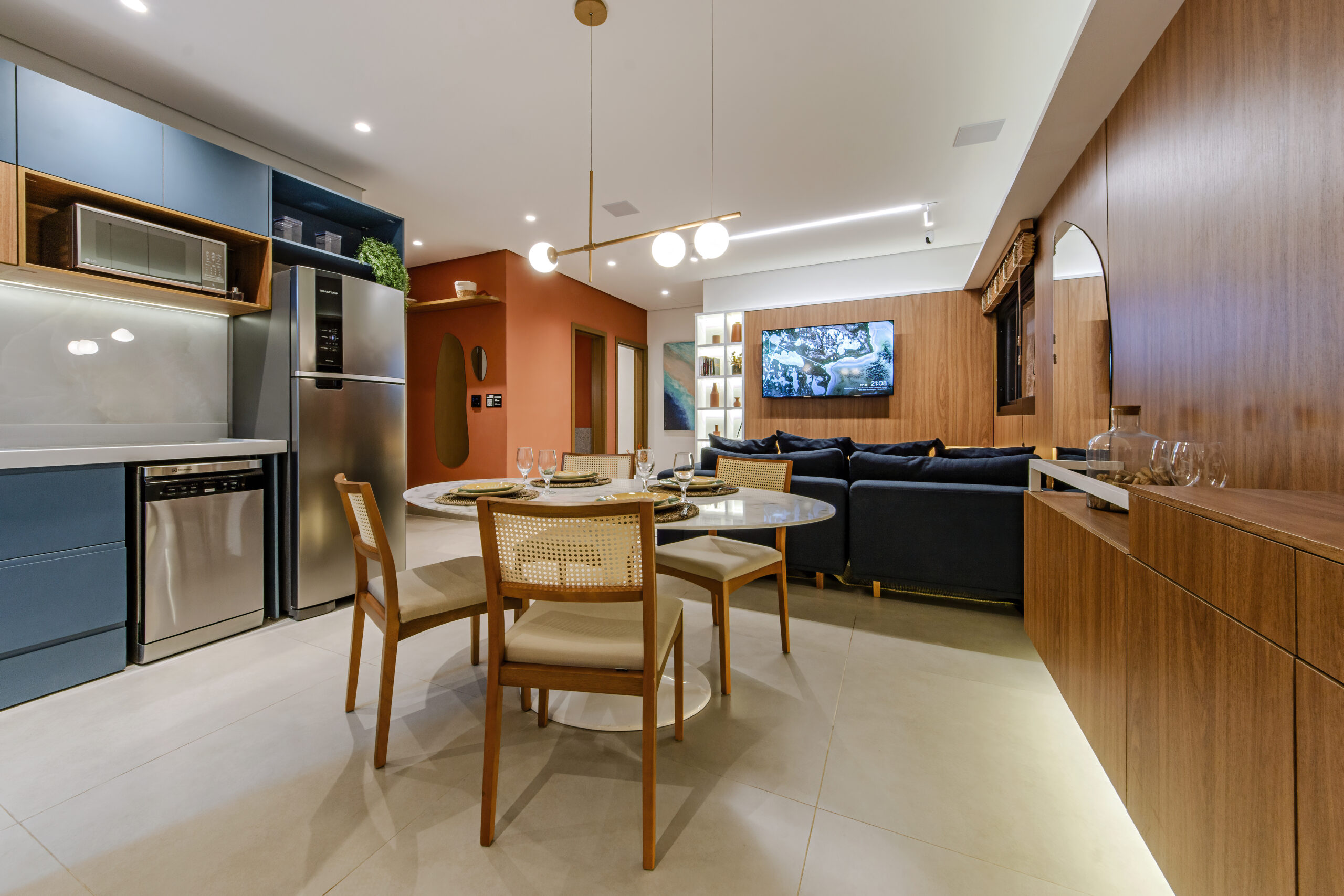 Ambiente integrado com acabamentos de alto padrão, incluindo marcenaria em madeira, revestimentos modernos e iluminação embutida.